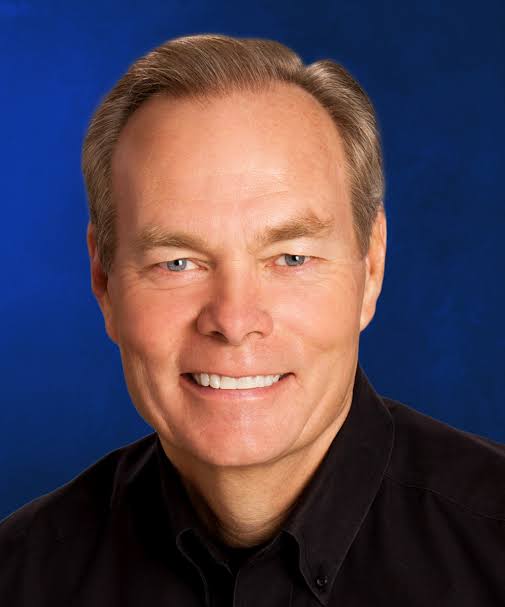 A man with grey hair and wearing black shirt.