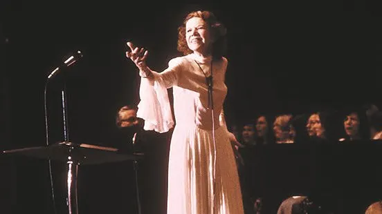 A woman in white dress holding up her hand.