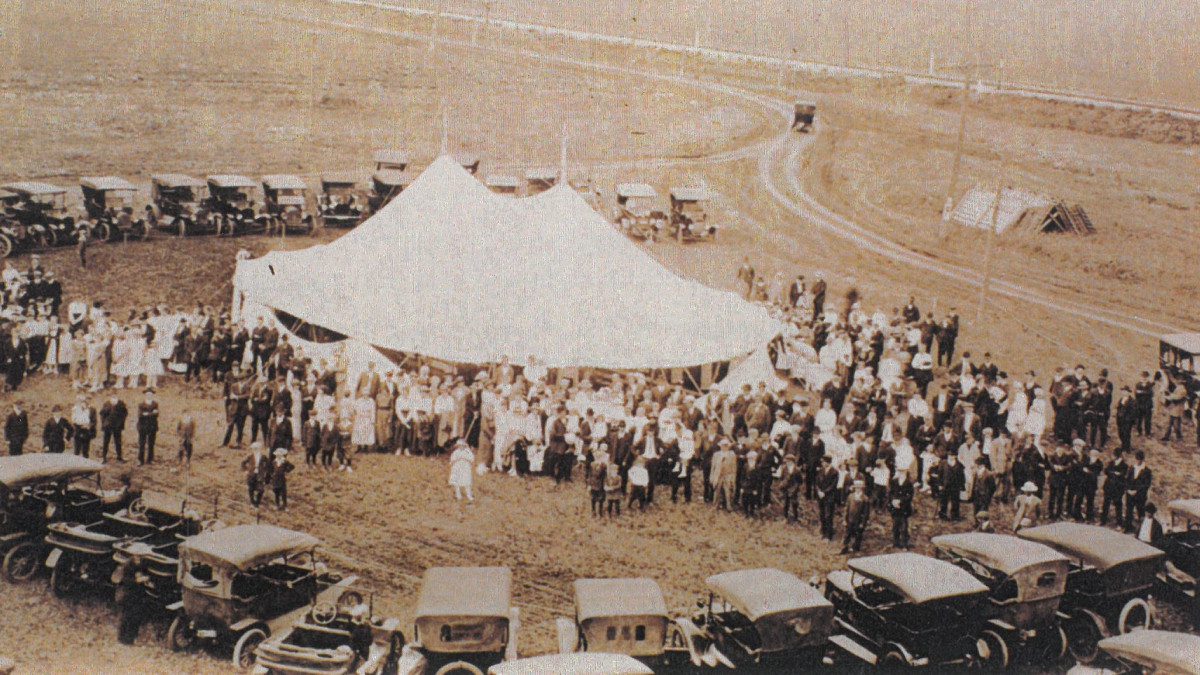 A group of people standing around an old tent.